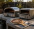 Gas and electric outdoor pizza ovens side by side on a bench in an Australian backyard